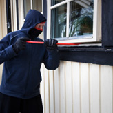 Home Invasions - A masked burglar trying to crowbar a window open
