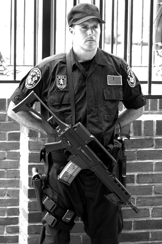Armed security guard standing with assault rifle across his chest