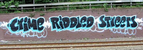 Graffiti on a wall that says "Crime riddled streets" in black and blue