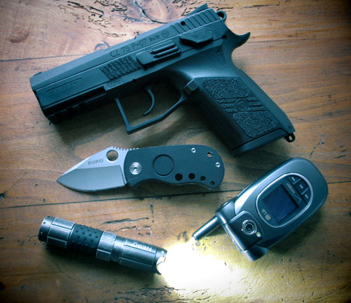 A handgun, knife, flashlight and cellphone on table