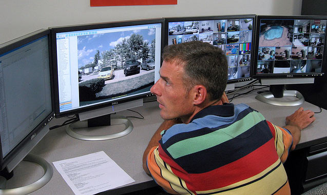 Man watching security video camera screens