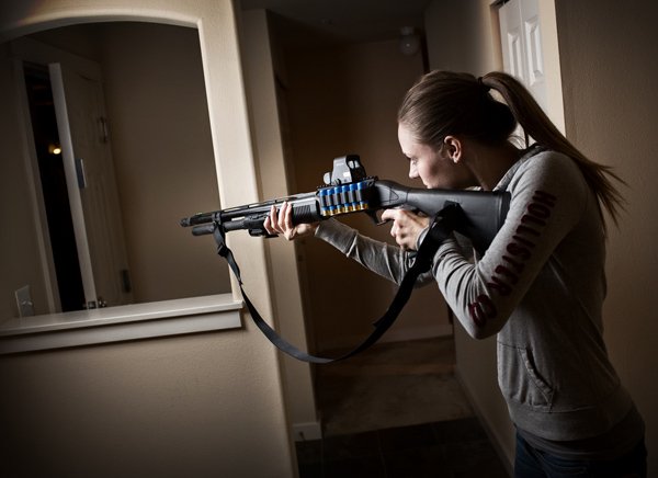 Home defense weapons - Woman pointing shotgun in her home at night