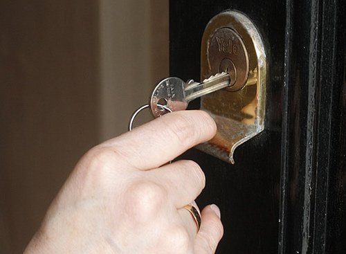 Home Security Door Lock - Someone putting a key into a Yale lock
