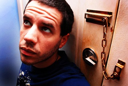 A man leaning up against a door with a security chain