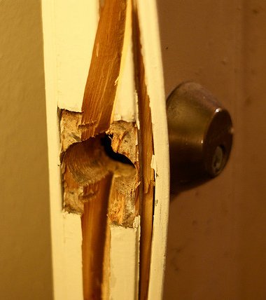 A door thats been kicked in. Split wood is visible.